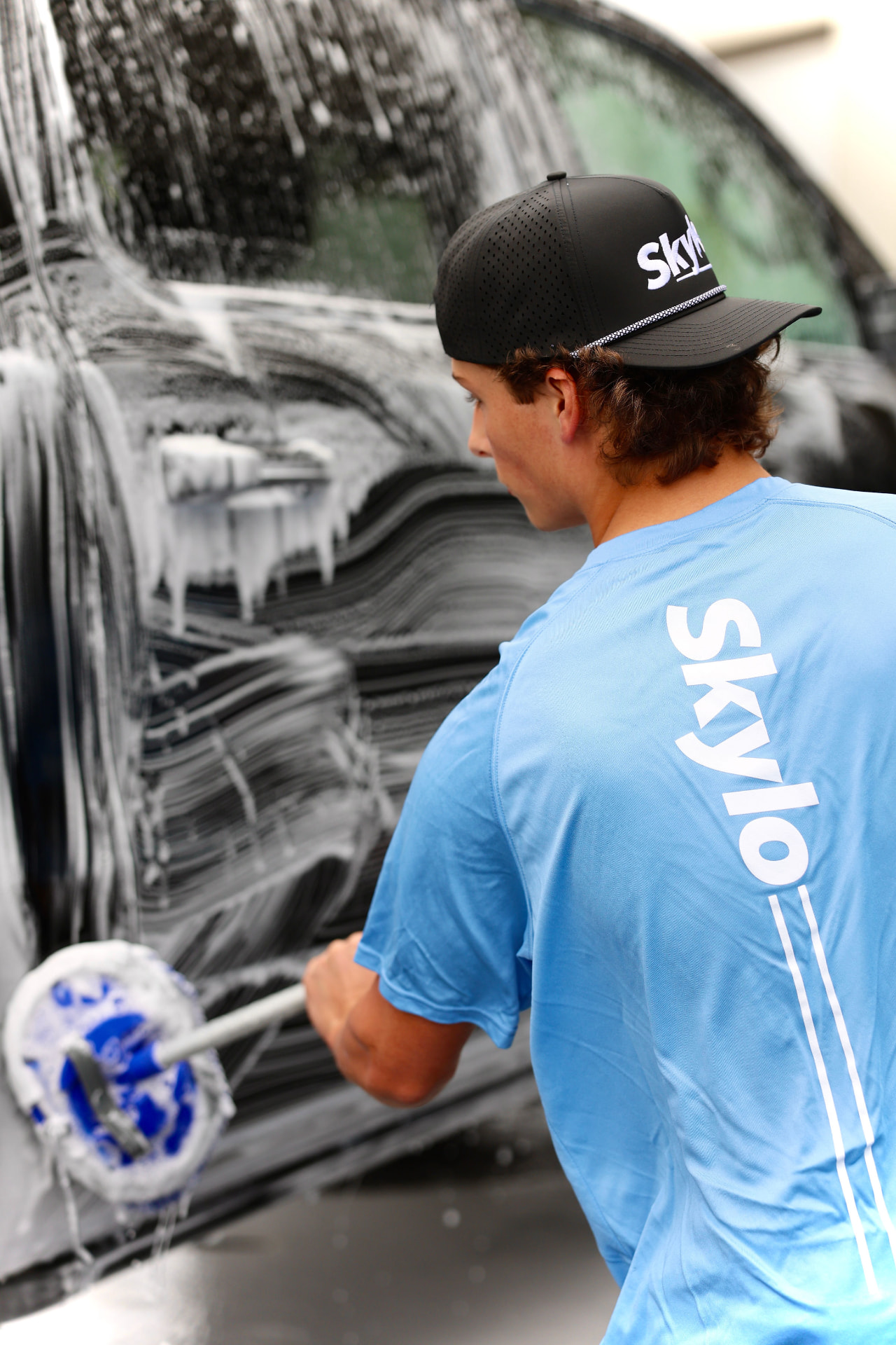 Skylo detailer foam-washing a car in a Lehi driveway