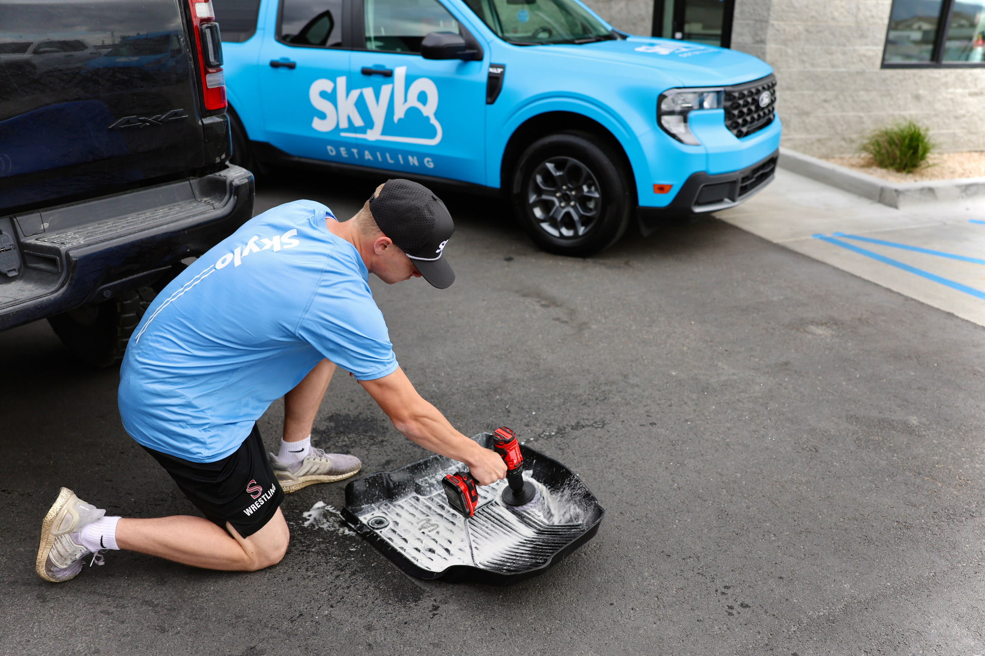 Skylo detailer deep-cleaning a car floor mat beside the Skylo truck in Orem