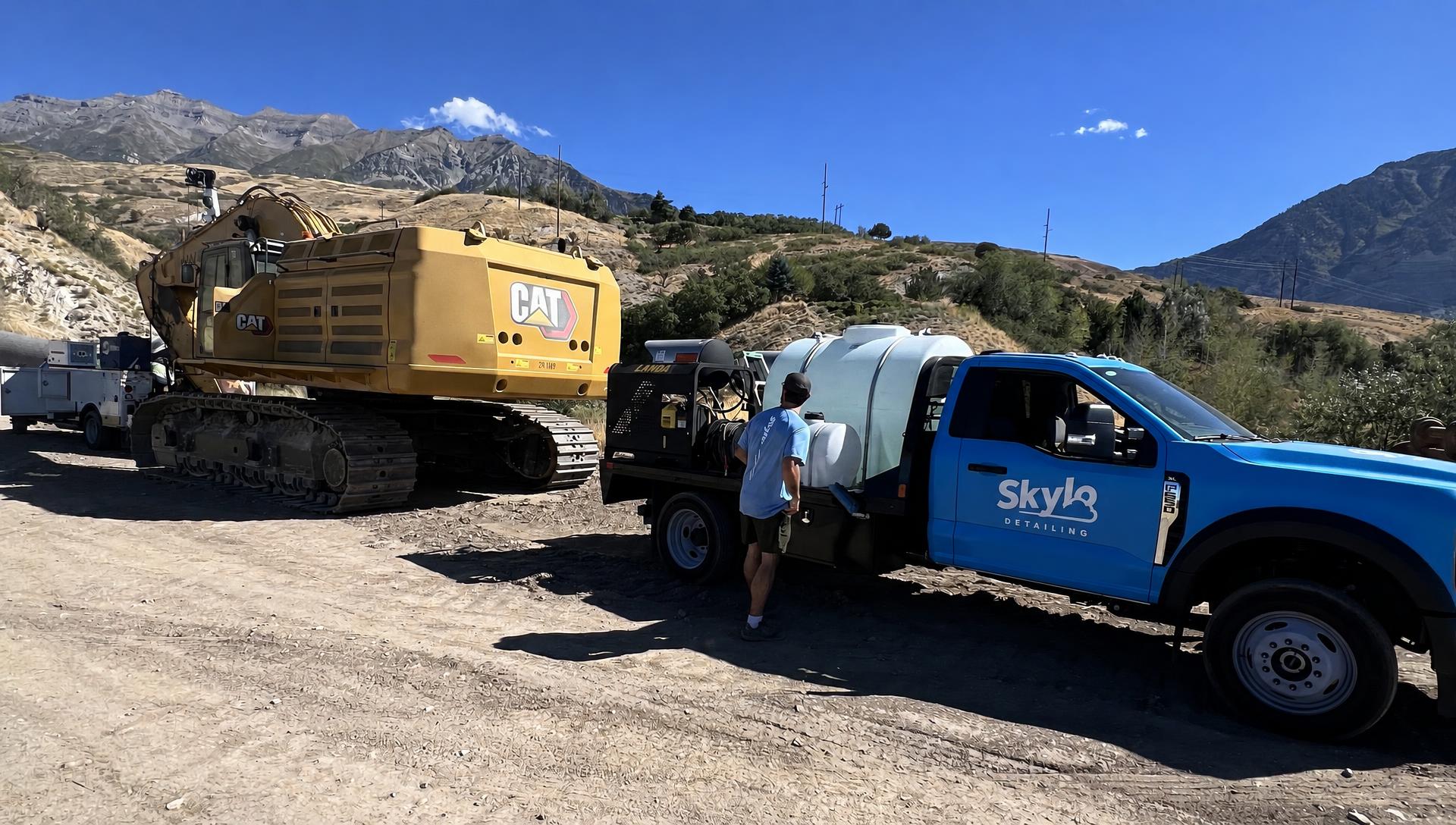 Skylo Detailing truck and tech at a Utah job site next to a CAT excavator